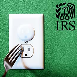 Fork approaching an electrical outlet on a green wall. Black IRS logo. 